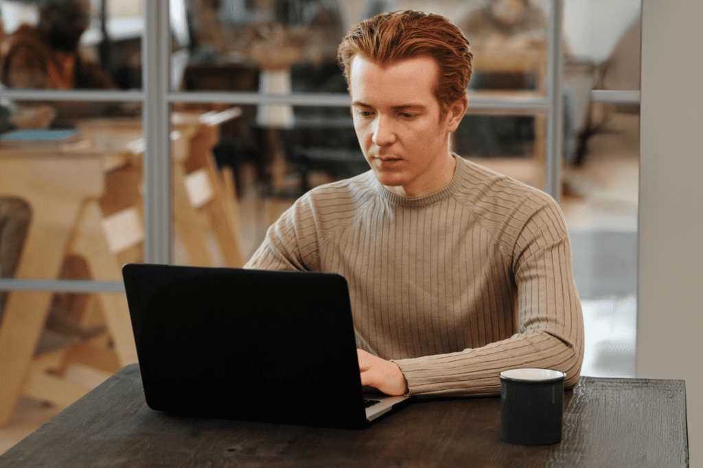 Ein Unternehmer, der allein im Büro, an seinem Laptop sitzt und arbeitet.