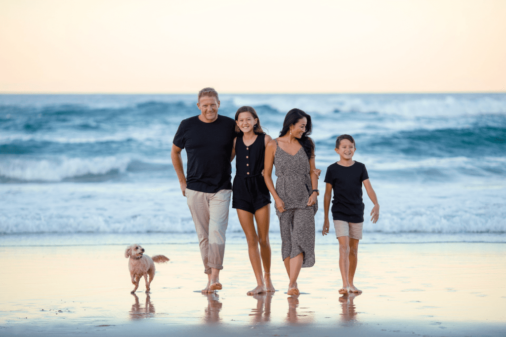 Eine Familie mit einem Hund, die am Strand Spazieren geht